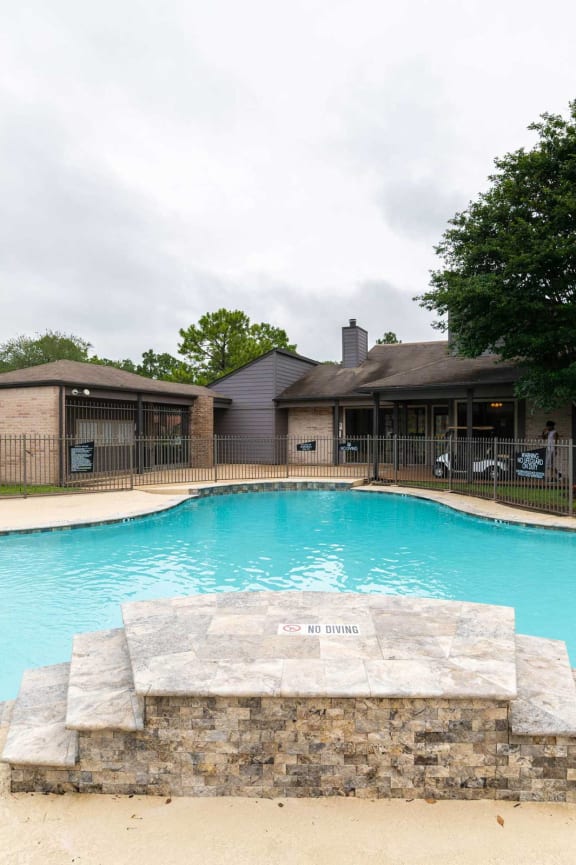 a swimming pool with orange chairs and a building in the background