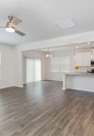 an empty living room with a kitchen in the background