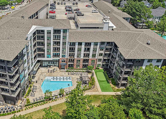 An aerial view of 915 Glenwood apartments with a swimming pool, green area with walking path,  and a parking lot.