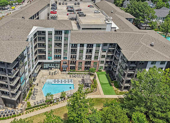 An aerial view of 915 Glenwood apartments with a swimming pool, green area with walking path,  and a parking lot.