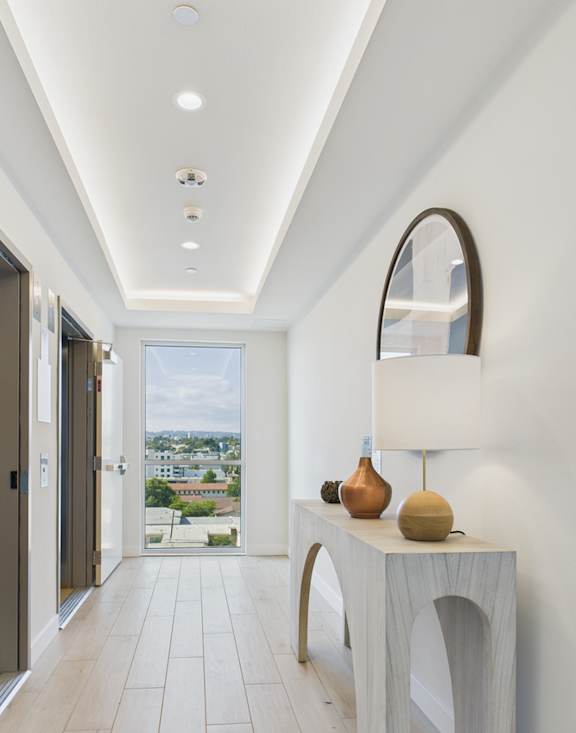A hallway with a white wall and a mirror on the right side.