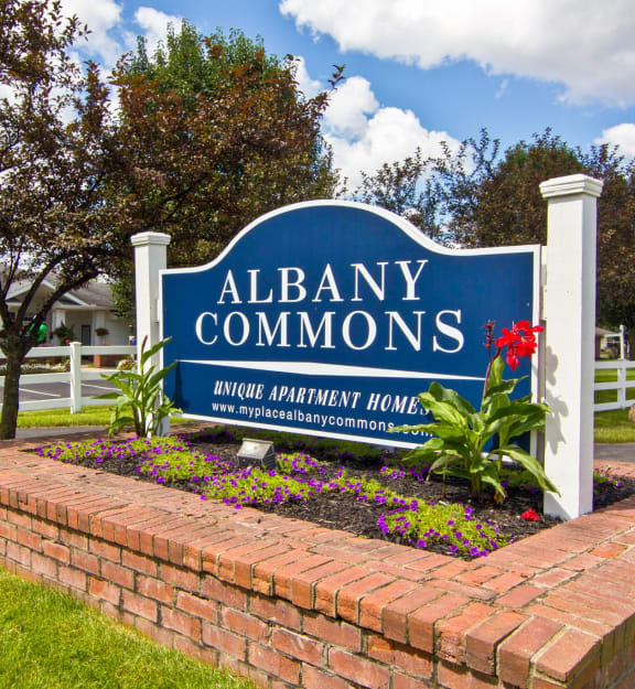 the sign commons in front of a brick retaining wall with flowers