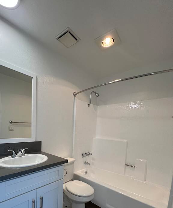 A white toilet is in a bathroom with a white sink.
