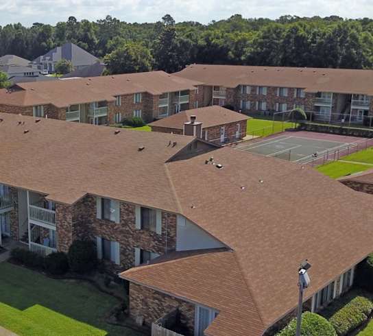 A large apartment complex with a parking lot in front.