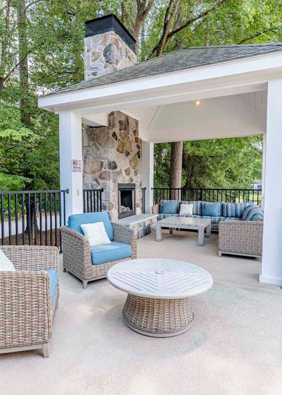 A patio with a white gazebo and wicker furniture.