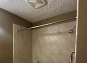 Thumbnail 7 of 17 - A white toilet is in a small bathroom with a walk-in shower.