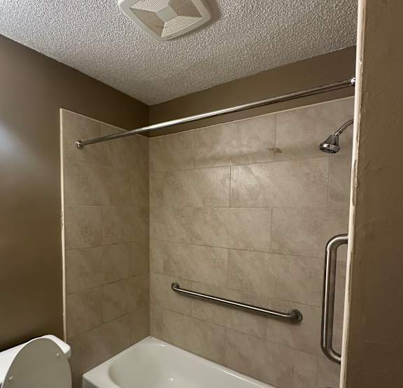 A white toilet is in a small bathroom with a walk-in shower.