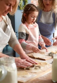a woman and two children making food on a table
