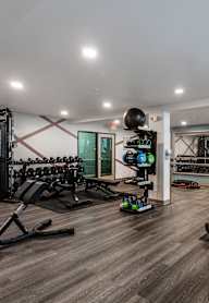 a gym with treadmills and other exercise equipment on a wooden floor