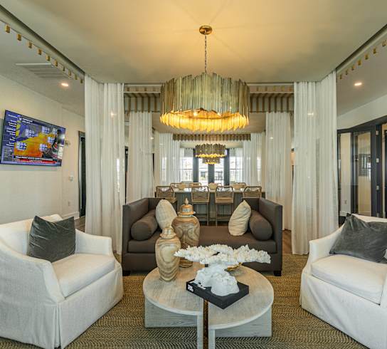 a living room with white furniture and a large chandelier