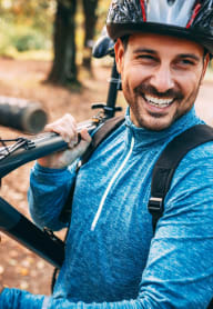 Man Wearing Helmet Smiling while Carrying Bike