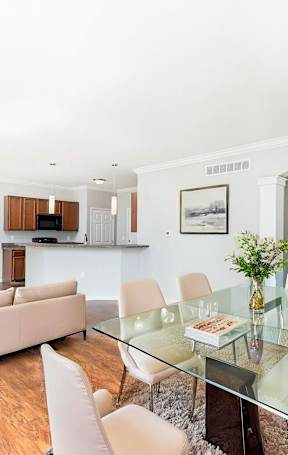 A modern living room with a glass table and white chairs.