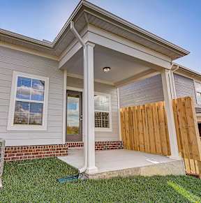 A house with a covered front porch and a heat pump outside.