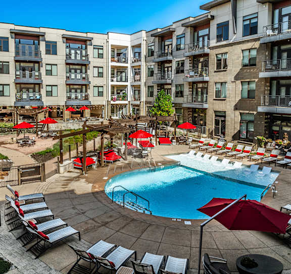 an aerial view of an apartment complex with a swimming pool with red accents in Carmel, IN