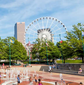 a fountain in a park with a ferris wheel in the background