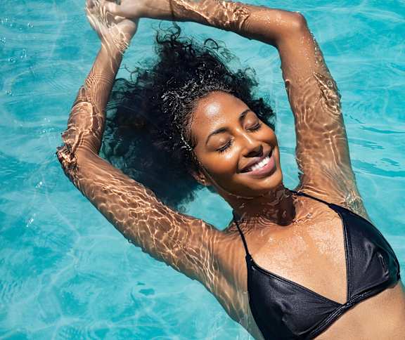 A woman in a black bikini is floating in a pool.