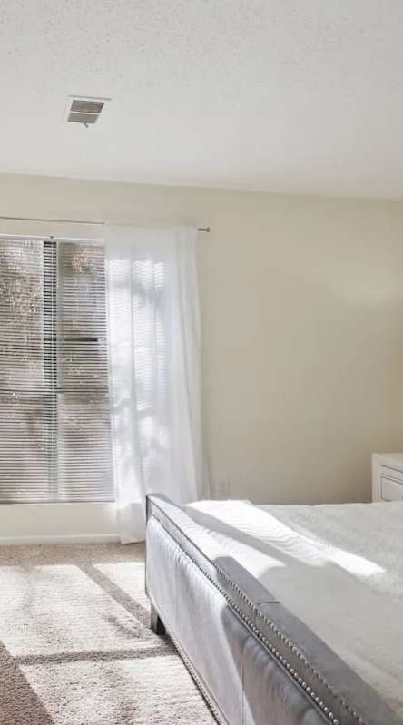 Bedroom with a bed and nightstand with a large window in our Peachtree Corners apartments.