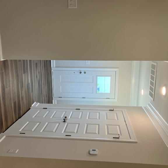A white ceiling with a square light fixture and a window.