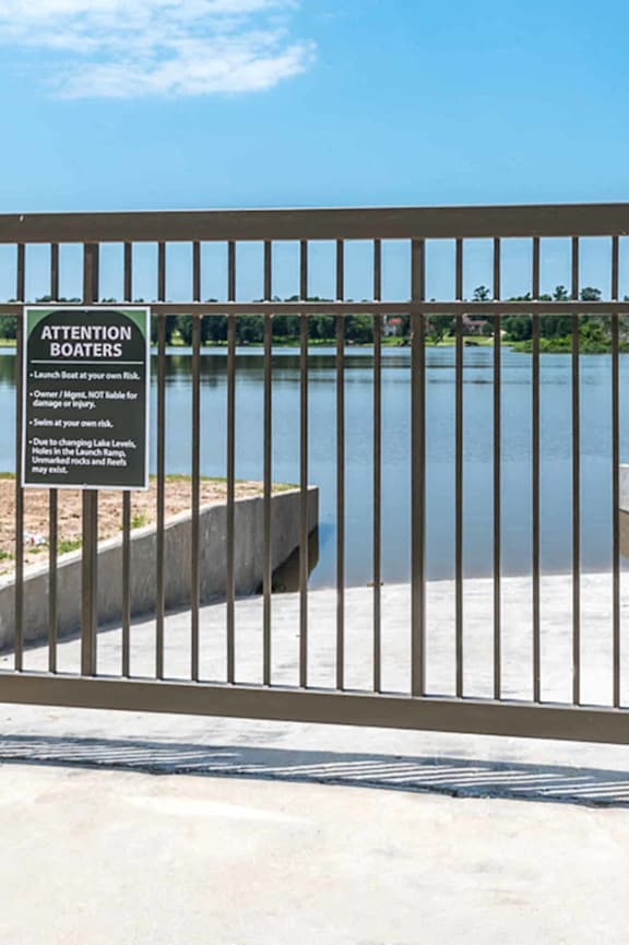 A metal gate with a sign on it in front of a body of water.