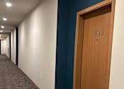 Thumbnail 12 of 34 - A long hallway with a blue ceiling and a door at the end.