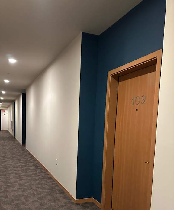 A long hallway with a blue ceiling and a door at the end.