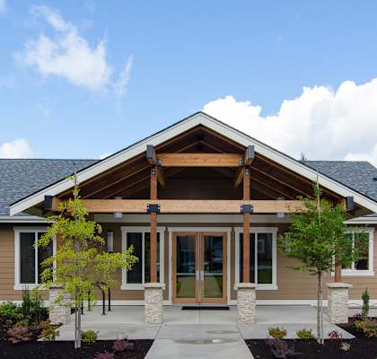 A building with a brown roof and tan walls with a walkway leading to the entrance.