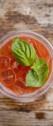 a glass of tomato juice with basil on the top