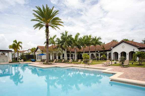A large swimming pool in front of a building with palm trees.
