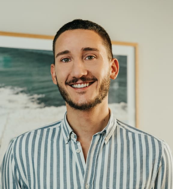 a man in a striped shirt standing in front of a painting