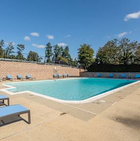 A pool with sun loungers and a fence.