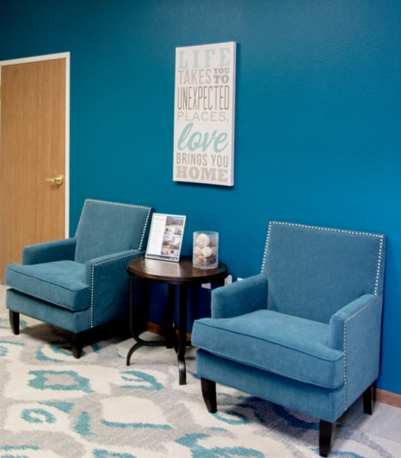 a waiting room with two blue chairs and a coffee table