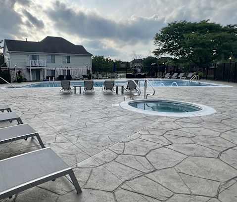 A pool area with a hot tub and lounge chairs.