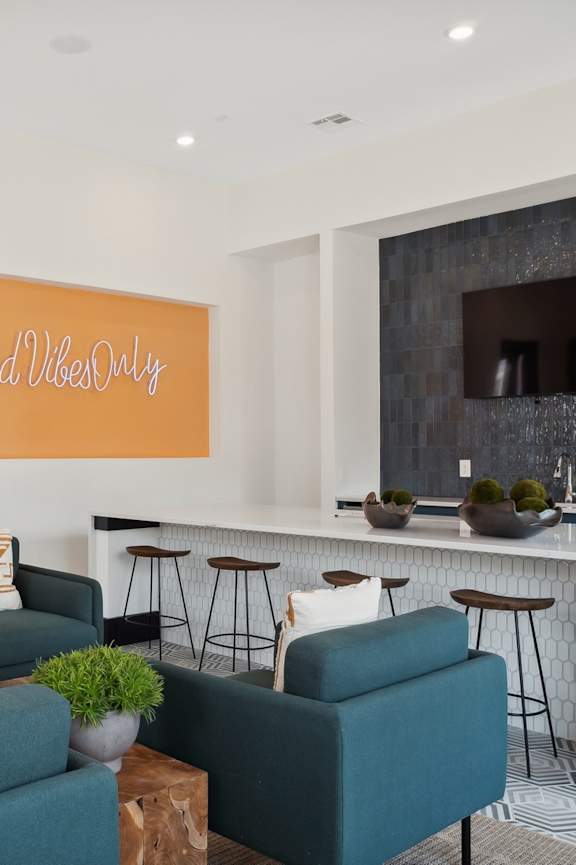 A living room with a green couch and a sign that says "Good Vibes Only".