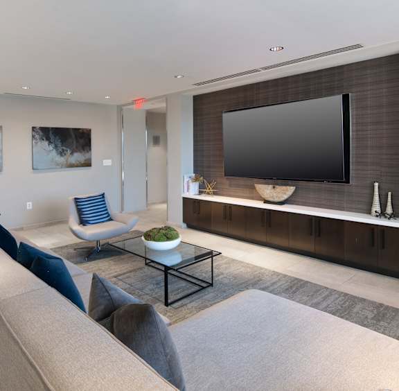 A modern living room with a grey sofa and a black television.