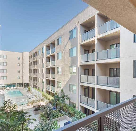 A modern apartment building with a pool and palm trees at Wilshire Valencia Apartment, California