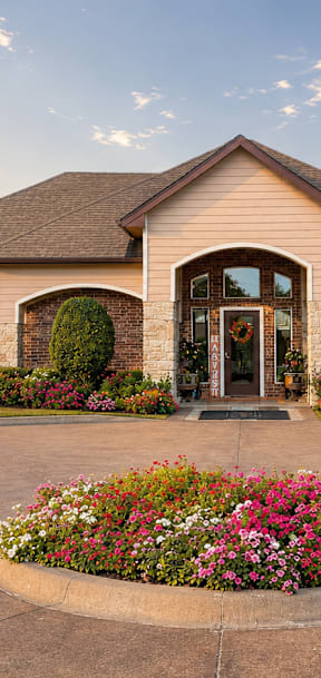 A house with a driveway and a flower bed in front.