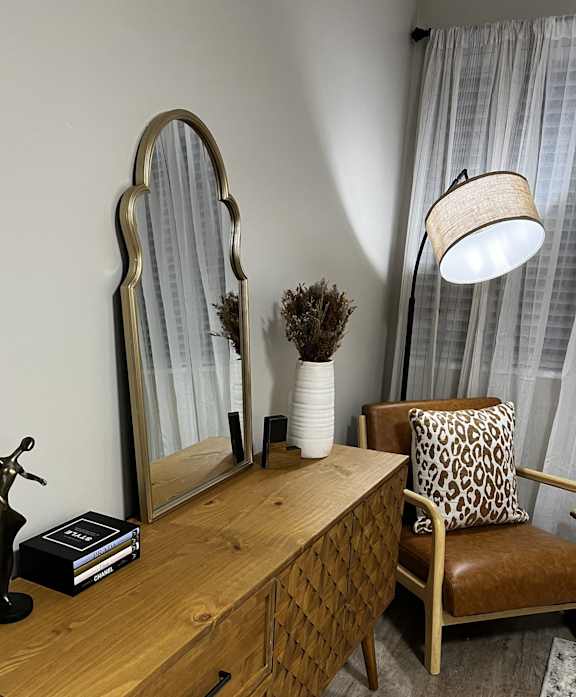 a wooden chest with a table and a broom and a table lamp