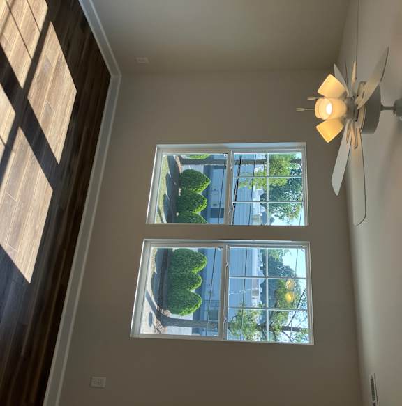 A ceiling fan with lights is mounted on a wall in a room with a window.