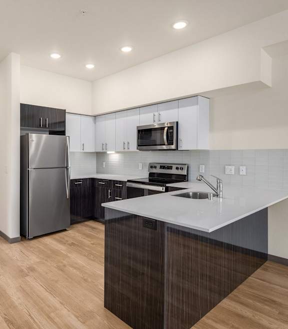 A kitchen with a refrigerator, microwave, and sink.