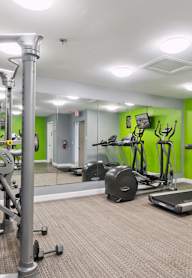 A gym with a variety of equipment including treadmills, weights, and exercise machines.