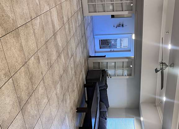 A hallway with a tiled wall and a mirror on the wall.