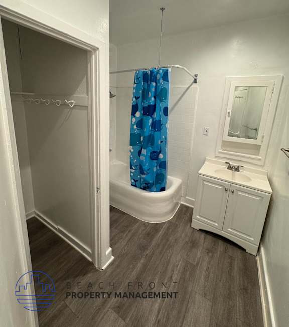 A bathroom with a white cabinet, a blue shower curtain, and a white toilet.