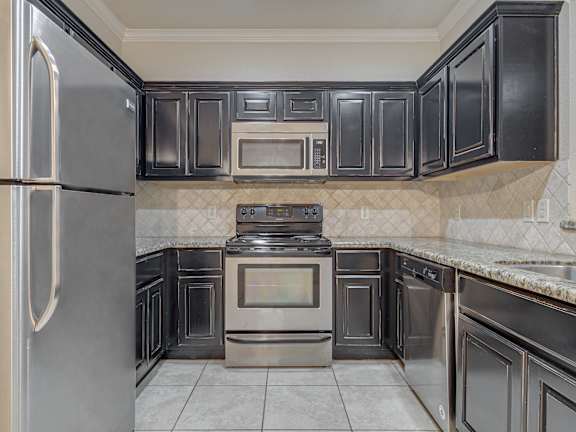 A kitchen with black cabinets and stainless steel appliances. at Logan Ridge Apartments, Apartments, San Marcos, TX