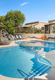 A swimming pool with a slide and sun loungers.