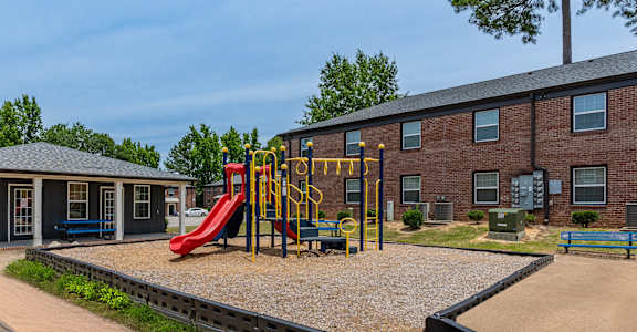 A playground with a red slide and a black ramp.