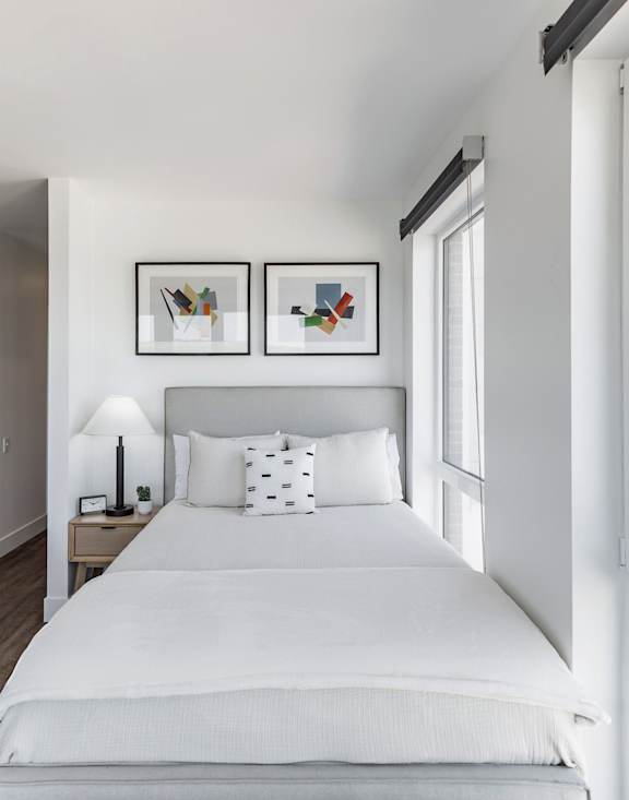 A bedroom with a large bed and a kitchen area in the background at Anthem House Apartment, Huntsville, AL, 35806