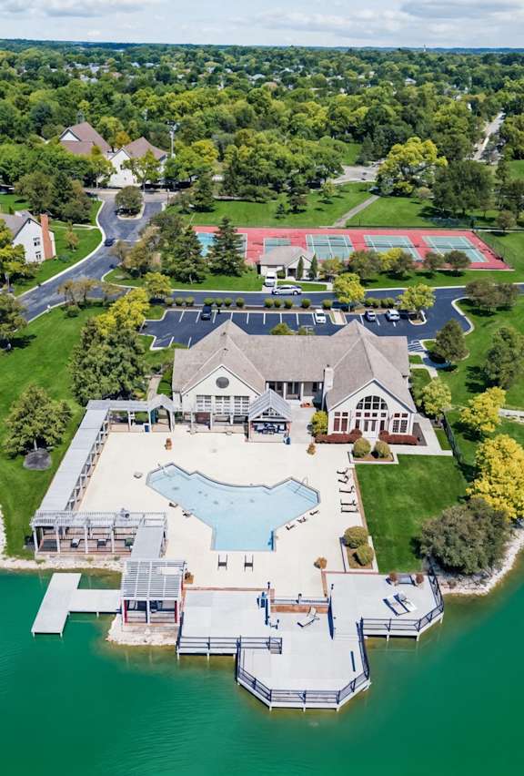 a mansion with a large pool in a grassy area next to a lake