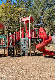 A playground with a red slide and a green and red climbing structure.