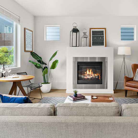 A living room with a grey couch, a fireplace, and a painting on the wall.