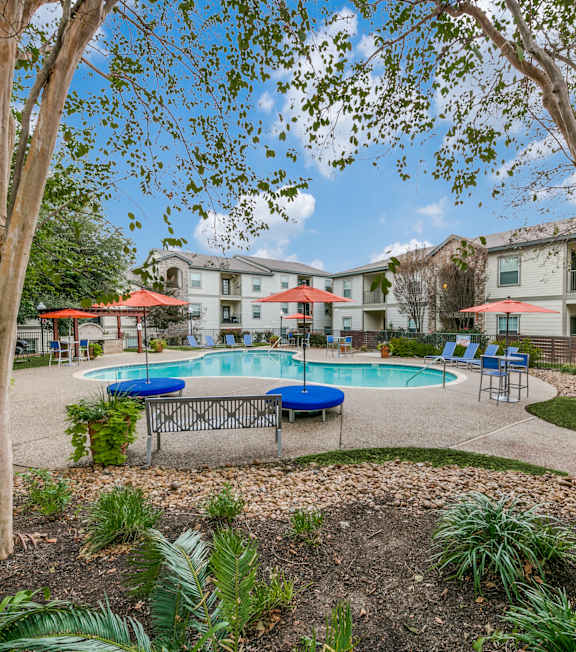 A pool surrounded by trees and chairs.
